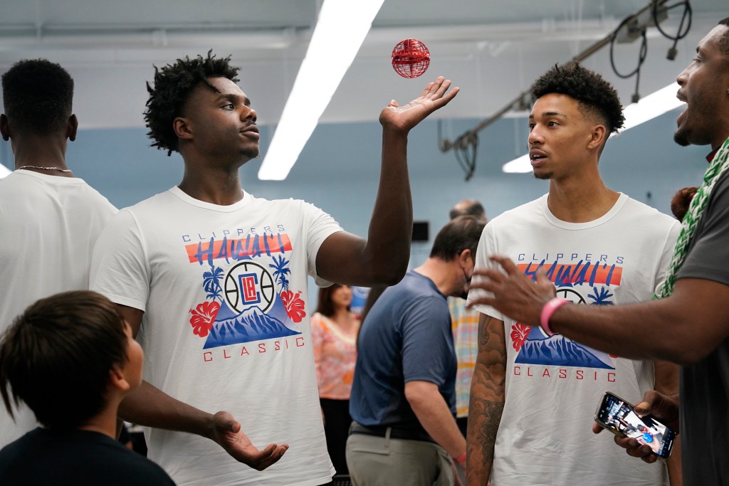 Los Angeles Clippers rookies Kobe Brown, from left, Jordan Miller and former player Craig Smith marvel at a flying ball in the Washington Middle School technology lab Thursday, Oct. 5, 2023, in Honolulu. The LA Clippers Foundation partnered with Hawai’i Tourism Authority and the Hawaii Department of Education to refurbish the school’s technology lab. (Kevin Fujii/Civil Beat/2023)