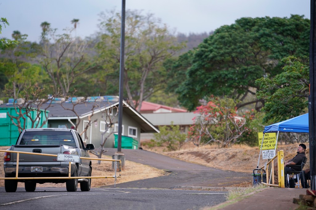 A security guard sits outside of Princess Nahienaena Elementary School Tuesday, Oct. 10, 2023, in Lahaina. Students will begin returning to classes in Lahaina next week after fall break. (Kevin Fujii/Civil Beat/2023)