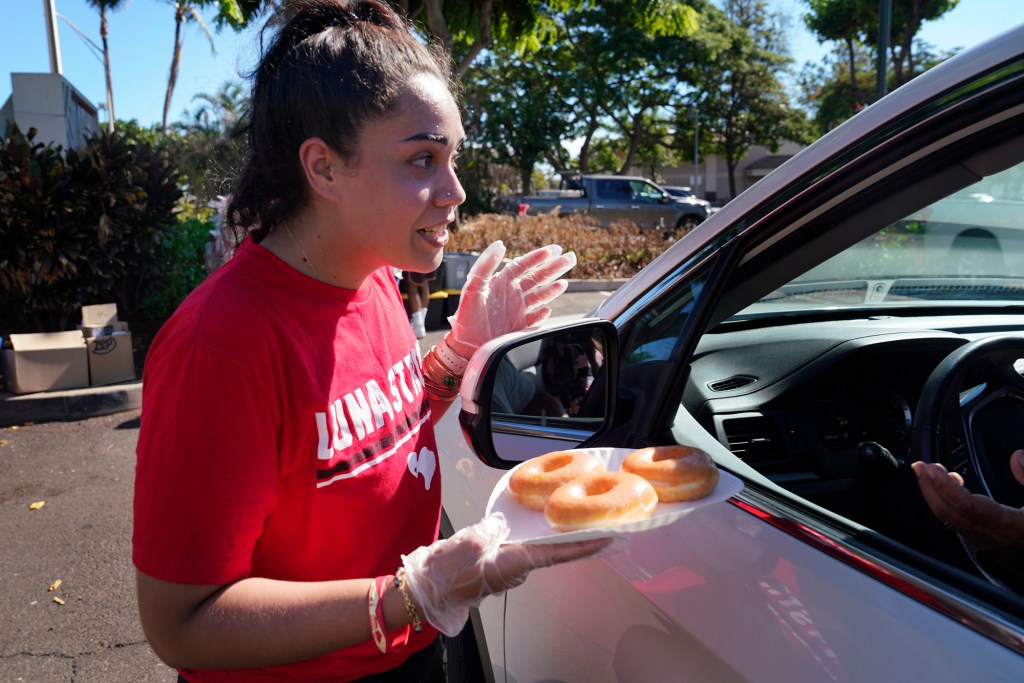 Lahainaluna High School alumni including organizer Lilinoe Elam-Fonohema hand out snacks to families with students returning to a Lahaina campus Monday, Oct. 16, 2023. The schools have been closed since the Aug. 8 fire and studying at other schools in Maui. (Kevin Fujii/Civil Beat/2023)