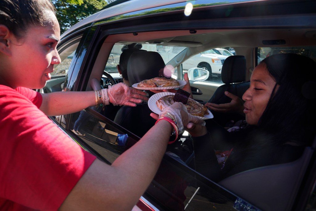 Lahainaluna High School alum Lilinoe Elam-Fonohema, from left, hands snacks to Lillian Kauvaka and EmmaMarie Rosenthal after their first day back at Lahainaluna High School Monday, Oct. 16, 2023. The schools have been closed since the Aug. 8 fire. Students have been studying at other schools in Maui. “It was good to be back.” Kauvaka said. “But I forgot how many hills and stairs we used to have to climb everyday and it’s much hotter here.” (Kevin Fujii/Civil Beat/2023)