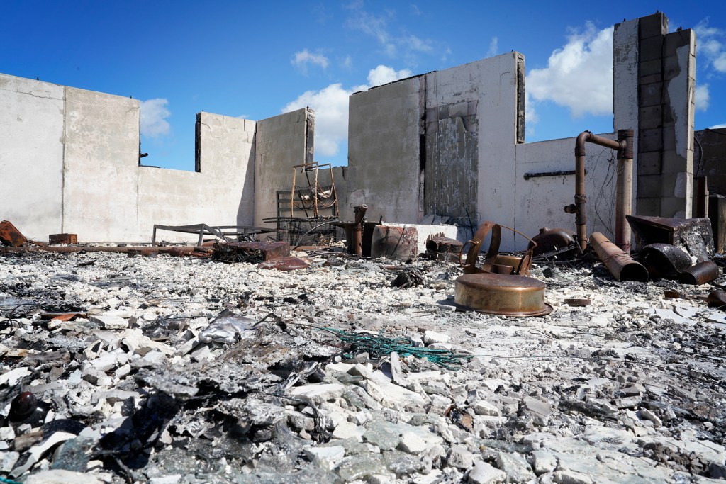 Truth Excavation sprayed a soil stabilizer on burned ash and debris inside of a burned-out house Wednesday, Oct. 18, 2023, in Lahaina. Known by its brand name “Soiltac,” once dry, potential hazardous material from burned debris and ash will remain on the ground and not become airborne particles. It is difficult to visually discern what has been sprayed. But walking on the dried application of soil stabilizer is noticeably softer. (Kevin Fujii/Civil Beat/2023)