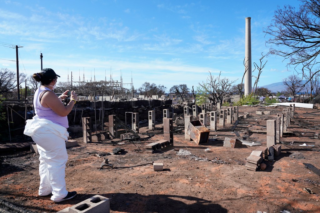U’i Kahue-Cabanting photographs the licensed nursery she and Mario Siatris maintained Monday, Nov. 13, 2023, near the house they shared in Lahaina. The Pioneer Mill smokestack still stands after the Aug. 8 fire. (Kevin Fujii/Civil Beat/2023)