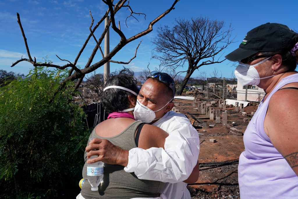 Neighbor Luella Haia hugs Mario Siatris and U’i Kahue-Cabanting after seeing each other and their homes Monday, Nov. 13, 2023, in Lahaina. Their homes and neighborhood were destroyed in the Aug. 8 fire. (Kevin Fujii/Civil Beat/2023)