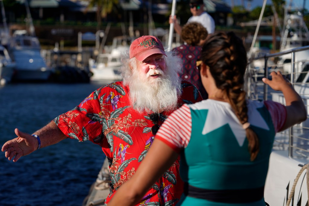 Ron Proctor hugs Alii Nui crew member Chloe Marino after their Sunset Sail Santa Cruise Saturday, Nov. 25, 2023, in Maalaea Harbor in Wailuku. Proctor has played Santa for more than 25 years. He lost his Lahaina home and belongings, including the hand-made Santa suit his daughter made, in the Aug. 8 fire. (Kevin Fujii/Civil Beat/2023)