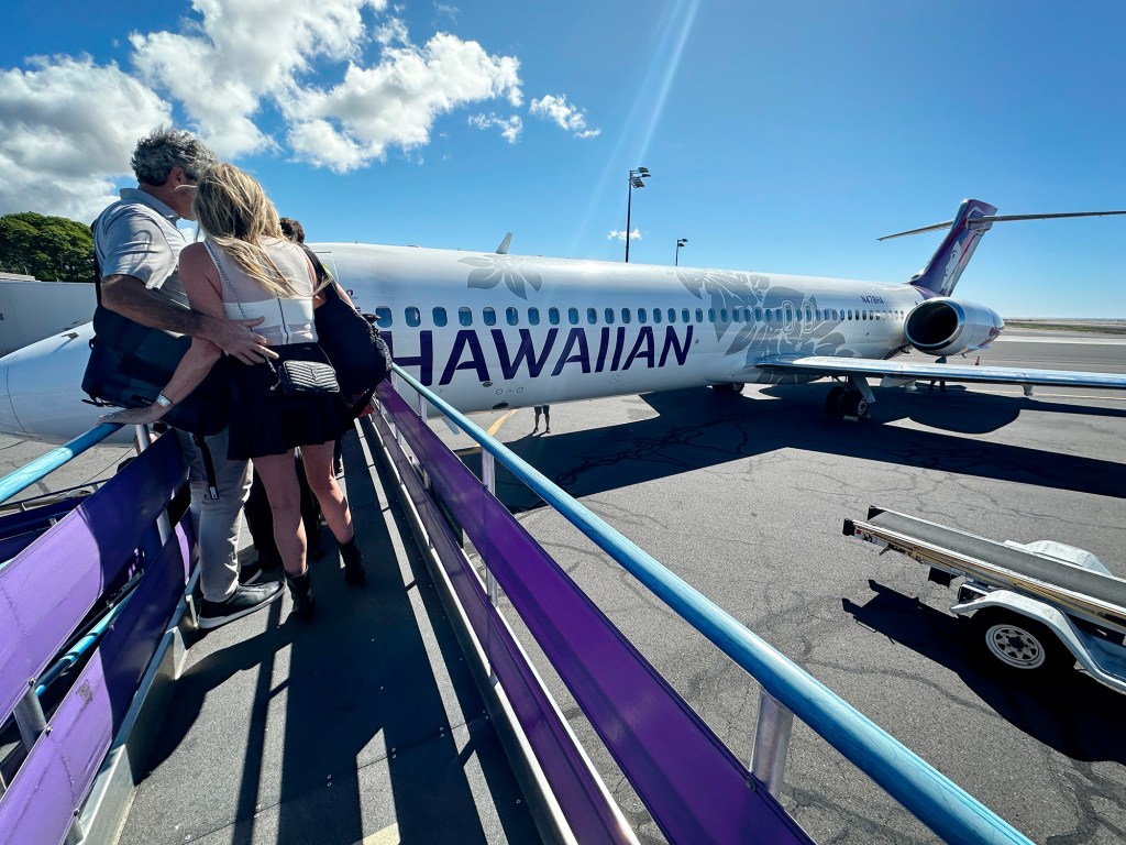 A couple boards a Hawaiian Airlines inter-island Boeing 717s at the Ellison Onizuka Kona International Airport Thursday, Dec. 14, 2023, at Keāhole on the Big Island of Hawaii . (Kevin Fujii/Civil Beat/2023)