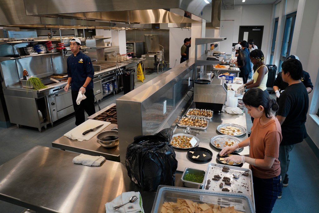 Waipahu High School Integrated Academy Learning Center’s Academy of Professional and Public Services students make pupus fo attendants of the ceremonial blessing Friday, Dec. 1, 2023, in Waipahu. The center offers students the opportunity to learn trades and skills. (Kevin Fujii/Civil Beat/2023)