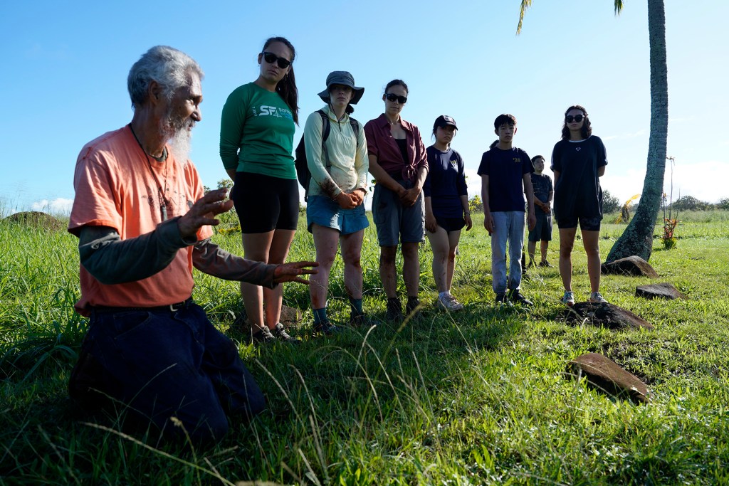 Tom Lenchanko, left, with the Civic Club of Wahiawa shares the history of the Kukaniloko Birthstones to tree-planting volunteers Saturday, Dec. 2, 2023, at the State Monument Kukaniloko Birthstones in Wahiawa. Carbon Neutrality Challenge co-founder Asryelle Mora Rollo used this tree-planting event to time how long it would take volunteers to plant 200 native Hawaiian trees. It took 14 volunteers 40 minutes to plant the 200 koa and wiliwili saplings. (Kevin Fujii/Civil Beat/2023)
