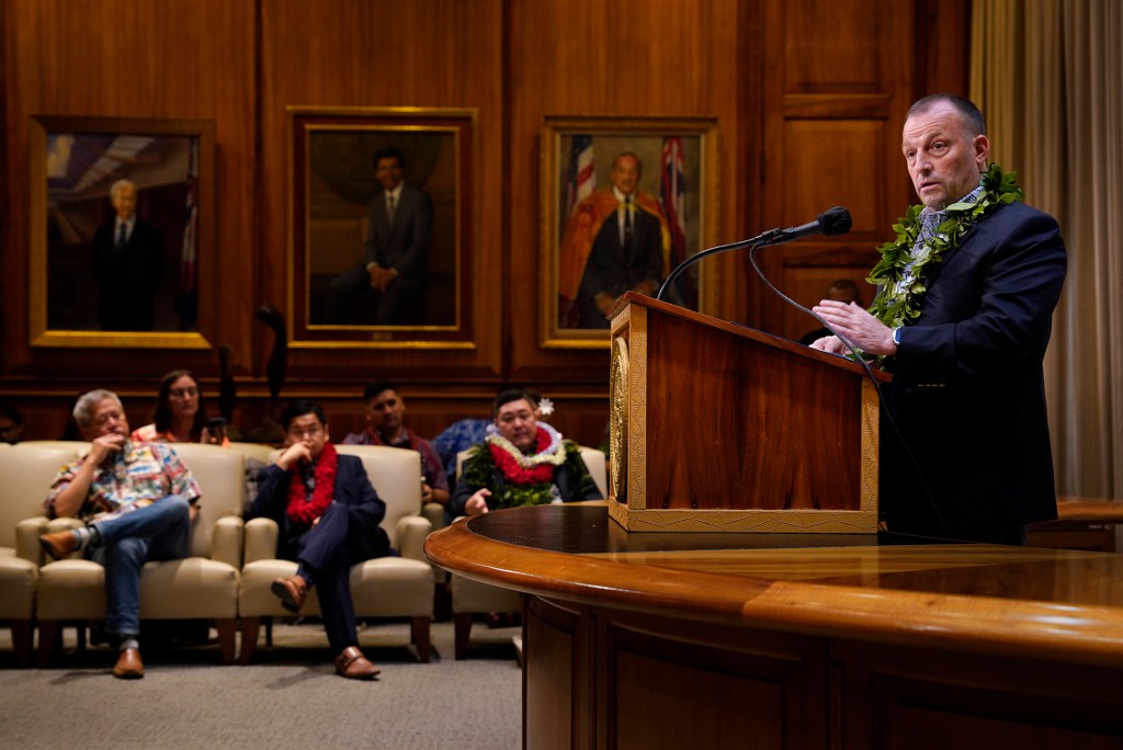 Gov. Josh Green updates the status of the Maui recovery Friday, Dec. 15, 2023, in Honolulu. House Speaker Scott Sakai, from left, Senator Troy Hashimoto and Rep. Tyson Miyake listen. Portraits of governors past line the mauka wall. (Kevin Fujii/Civil Beat/2023)