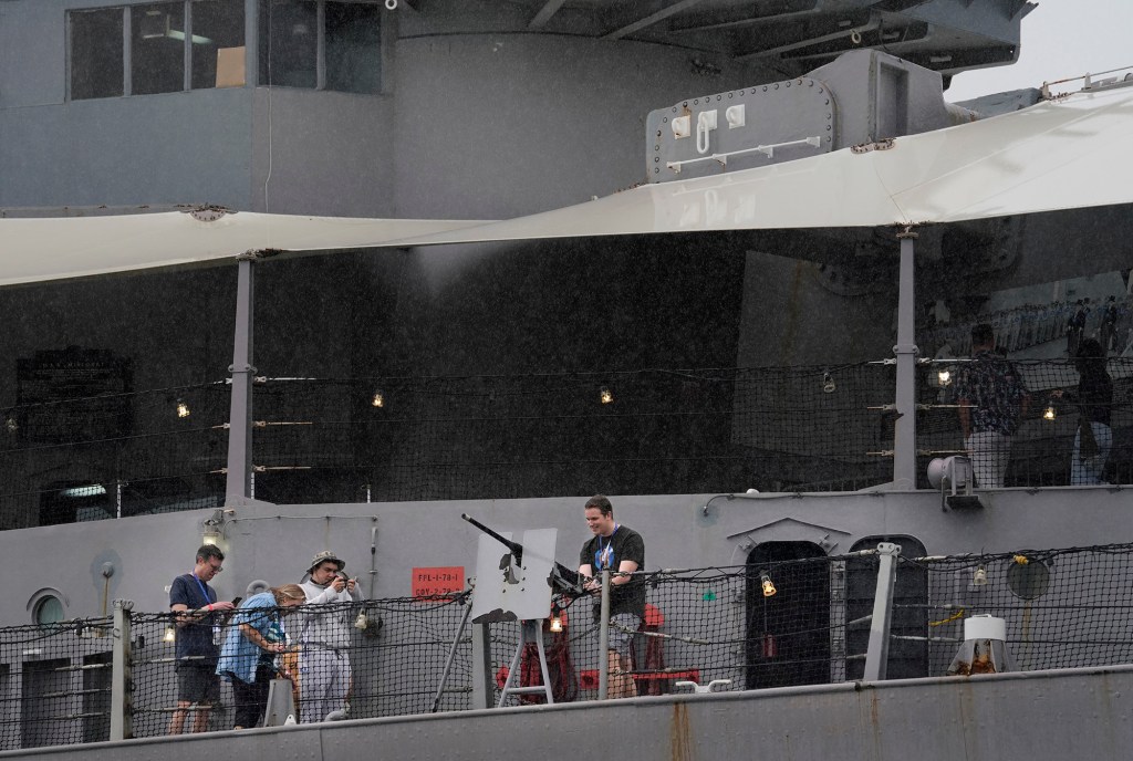 Tourists take pictures with a gun on the Battleship Missouri Memorial Wednesday, Dec. 20, 2023, at Pearl Harbor in Honolulu. The battleship turned floating museum was the site of the September 2, 1945, surrender of Japan to the Allied Powers to end World War II. (Kevin Fujii/Civil Beat/2023)