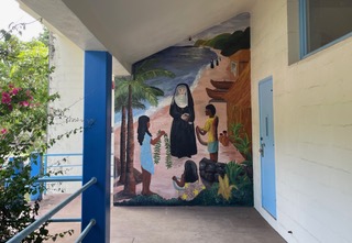 A mural in the Saint Francis School Souza Courtyard showing a Kalaupapa shoreline scene with a nun and Native Hawaiian children.