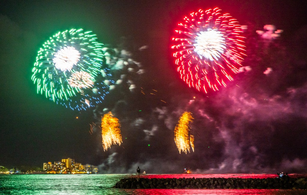 A lone spectator stands at the end of the rock pier at Kaisers and Publics surf spots to observe the Honolulu FestivalÕs concluding Nagaoka fireworks show visible from the vicinity of Queens Beach in Waikiki and Magic Island. The show lasted 15 minutes and is captured on March 10th, 2024. (David Croxford/Civil Beat/2024