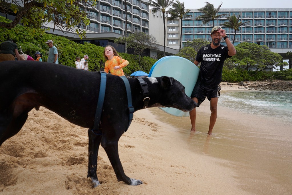 Aka and Myla Rezmovits, 7, of Hastings-on-Hudson, New York, wrap up a successful surf session with Rocky Canon at Kuilima Cove on Wednesday, March 27, 2024, at Turtle Bay Resort in Kahuku. Canon runs (North Shore Ocean Guides) NSOG Hawaii to share his love of the ocean with clients. (Kevin Fujii/Civil Beat/2024)