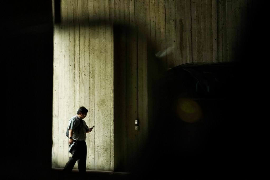 A pedestrian is reflected in a car’s side-view mirror entering the Capitol parking lot Tuesday, April 16, 2024, in Honolulu. (Kevin Fujii/Civil Beat/2024)