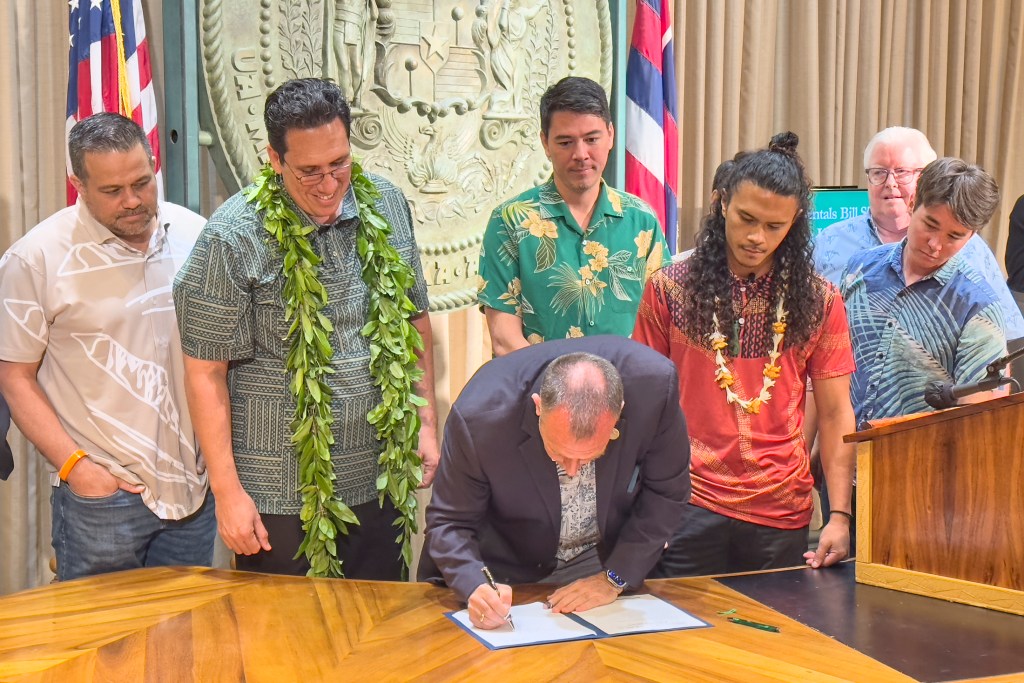 Governor Josh Green signed into law SB2919 on Friday May 3rd, 2024 which addresses the issue of illegal short-term rentals. SB 2919 aims to alleviate Hawaiʻi's housing crisis and increase housing levels throughout the state. This bill provides counties with home rule authority to see that vacation rentals are not allowed in communities that do not want them. It was instigated b y Lahaina Strong a grass roots movement headed by Paele Kiakona who spoke to those witnesses gathered to see the bill signed into law. (David Croxford/Civil Beat/2024)