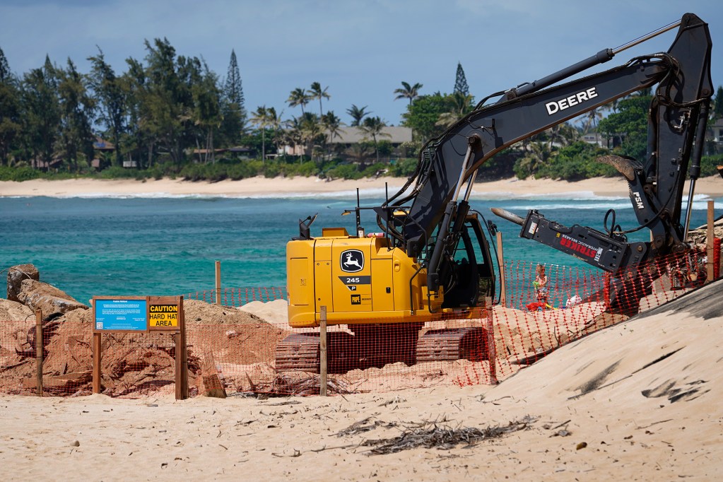 Workers remove a seawall at a Sunset Beach house while keiki play Tuesday, May 7, 2024, in Pupukea. (Kevin Fujii/Civil Beat/2024)