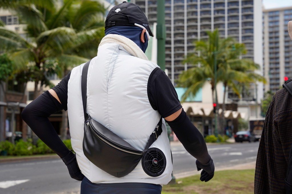 A tourist from Japan blocks as much UV rays as possible while walking in Waikiki Tuesday, May 13, 2024, in Honolulu. His vest circulates cool air. (Kevin Fujii/Civil Beat/2024)