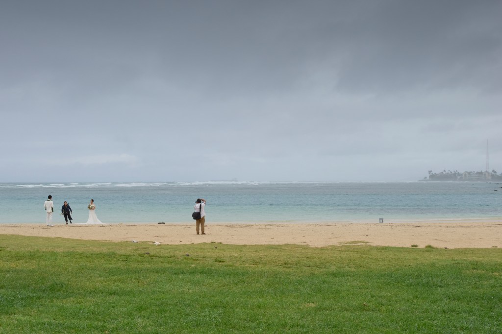A Kona low sitting about 450 miles North Northwest of Oahu is dragging tropical moisture up across the islands from the south. Predictions revealed anything from 1 to 3 inches of rain could fall as the storm stalls in its present position. Beaches like the one at Ala Moana Beach park were left empty save for the lone destination wedding couple whose photographer diligently worked to provide memorable images of the couple’s big day. Photographed May 16th, 2024 (David Croxford/Civil Beat/2024)