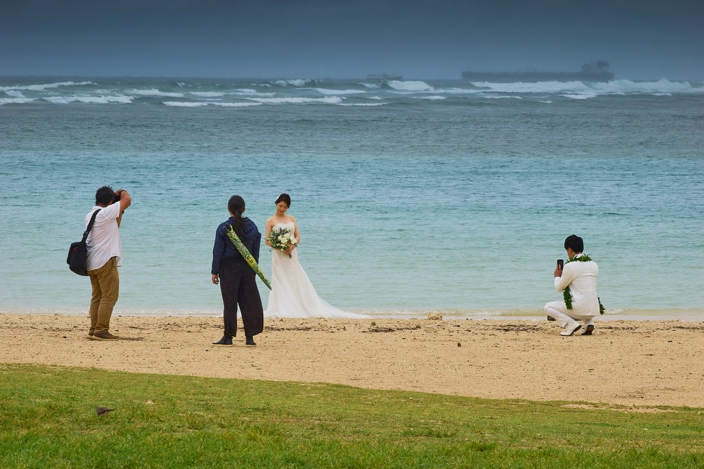 A Kona low sitting about 450 miles North Northwest of Oahu is dragging tropical moisture up across the islands from the south. Predictions revealed anything from 1 to 3 inches of rain could fall as the storm stalls in its present position. Beaches like the one at Ala Moana Beach park were left empty save for the lone destination wedding couple whose photographer diligently worked to provide memorable images of the couple’s big day. Photographed May 16th, 2024 (David Croxford/Civil Beat/2024)