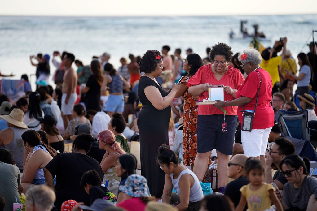 Nicole Mattox, from left, Carlita Ferguson and Roietta Goodwin from Sacramento, California, honor their mother and father at the 25th anniversary Shinnyo Lantern Floating Hawaii 2024 Monday, May 27, 2024, at Ala Moana Beach Park in Honolulu. Lanterns with messages are sent afloat to remember those who have passed. (Kevin Fujii/Civil Beat/2024)