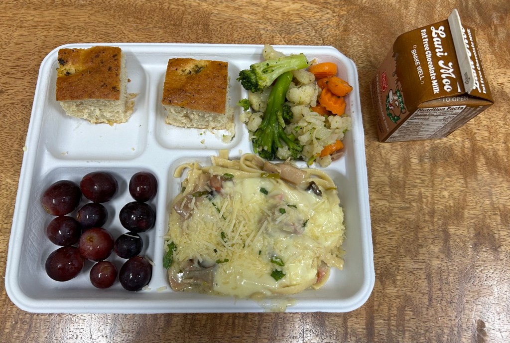 A school lunch at the Hawaii Academy of Arts and Science consists of chicken fettuccine, focaccia rolls and fruits and vegetables.