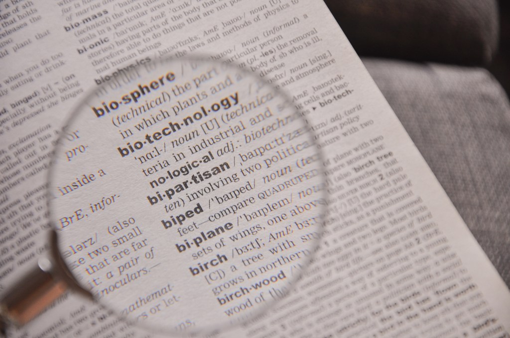 The definition of the word Bipartisan in a dictionary, under magnifying glass, translator and language concept