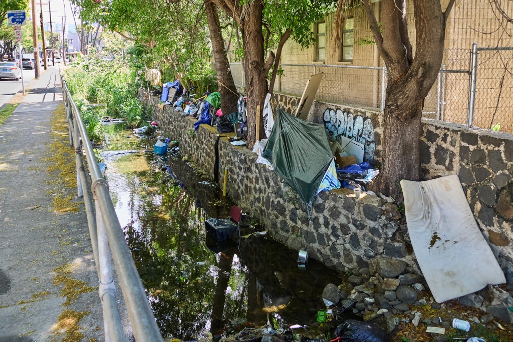 Along the Diamond Head side of Kalakaua Avenue there is a growing homeless encampment dotted along the stream that parallels the famously named street. Some of the tents surround a Bus stop within eyesight of the local Jack in the Box. The assortment of trash ranges from Shopping Carts to displaced Yeti water flasks and everything in between. Photographed Wednesday June 12, 2024(David Croxford/Civil Beat/2024)