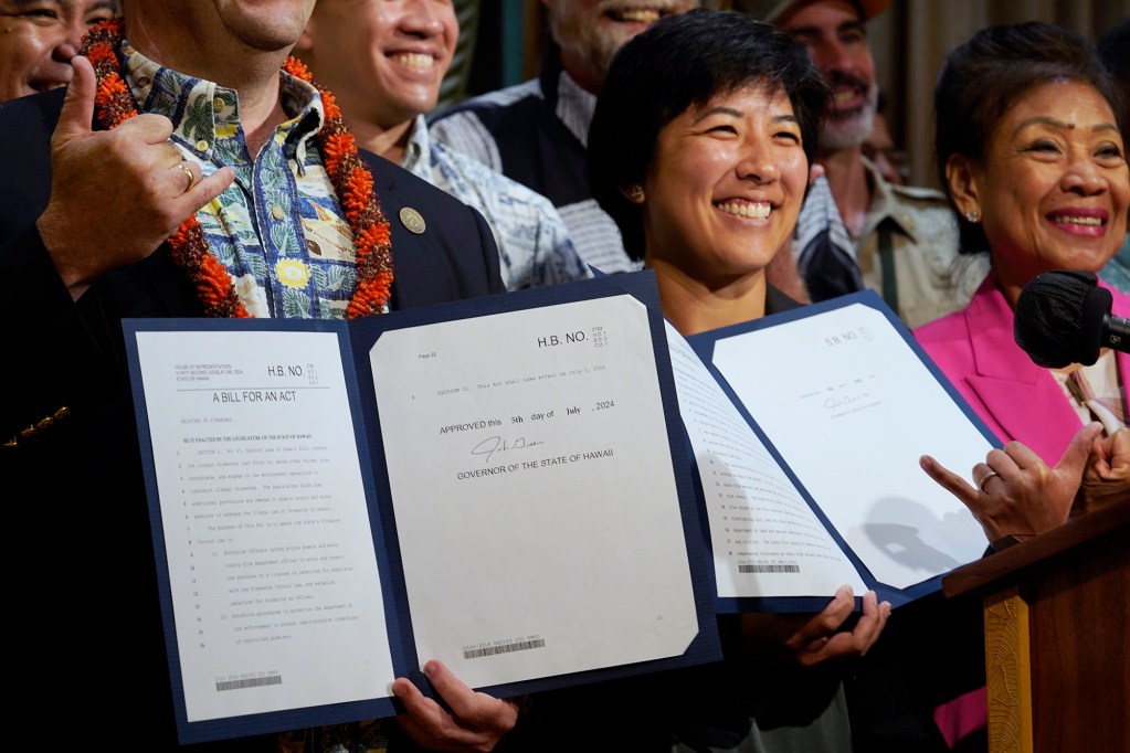 Gov. Josh Green and Rep. Linda Ichiyama hold bills signed into law Friday, July 5, 2024, in Honolulu. The four bills stem from the Aug. 8 fire which destroyed Lahaina and Upcountry Maui. (Kevin Fujii/Civil Beat/2024)