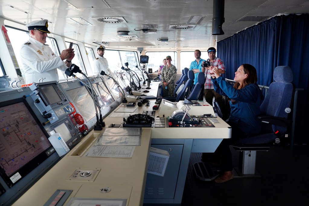 German Navy Ensign Wolfgang Hopf, left, photographs Hawaii News Now’s Annalisa Burgos sitting on the bridge of the frigate FGS Baden-Württemberg Wednesday, July 31, 2024, in Honolulu. The German Navy is participating in the Indo-Pacific Deployment which includes the Baden-Württemberg and combat supply ship FGS Frankfurt am Main as part of RIMPAC. (Kevin Fujii/Civil Beat/2024)