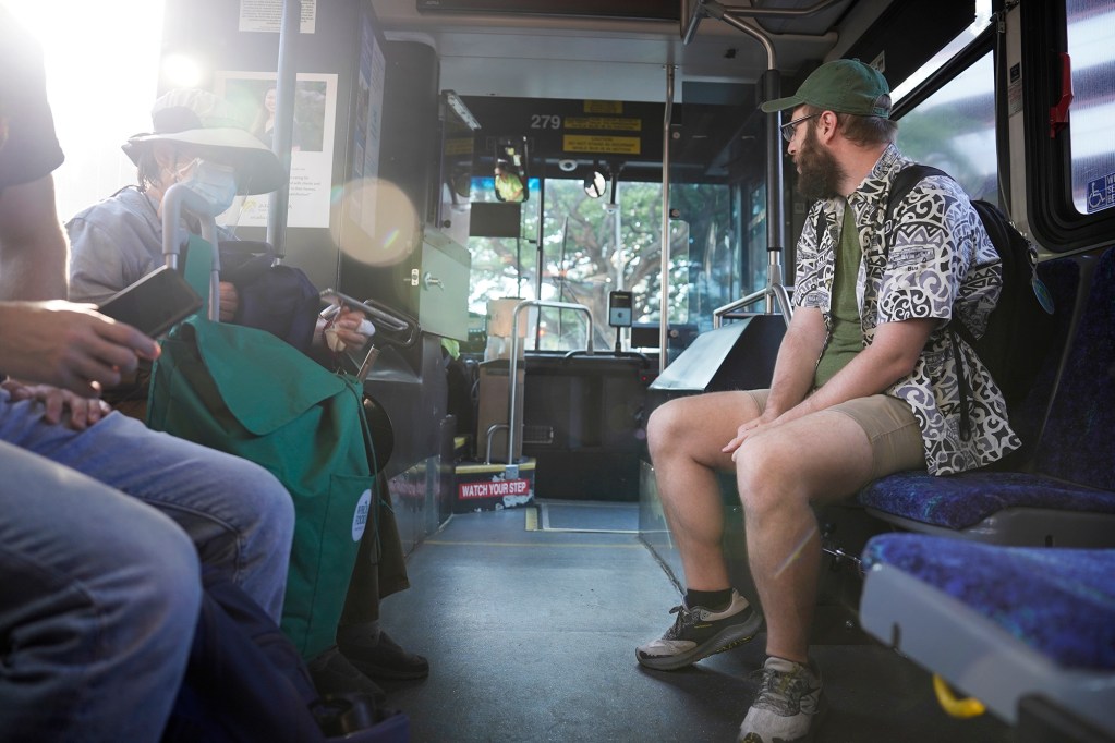 Passengers including Cathy Chow, left, and Reed Mershon, right, ride The Bus route 18 as it makes its last rounds Thursday, Aug. 15, 2024, in Honolulu. The route will be discontinued. Some regular riders have found a community with each other and the driver. (Kevin Fujii/Civil Beat/2024)