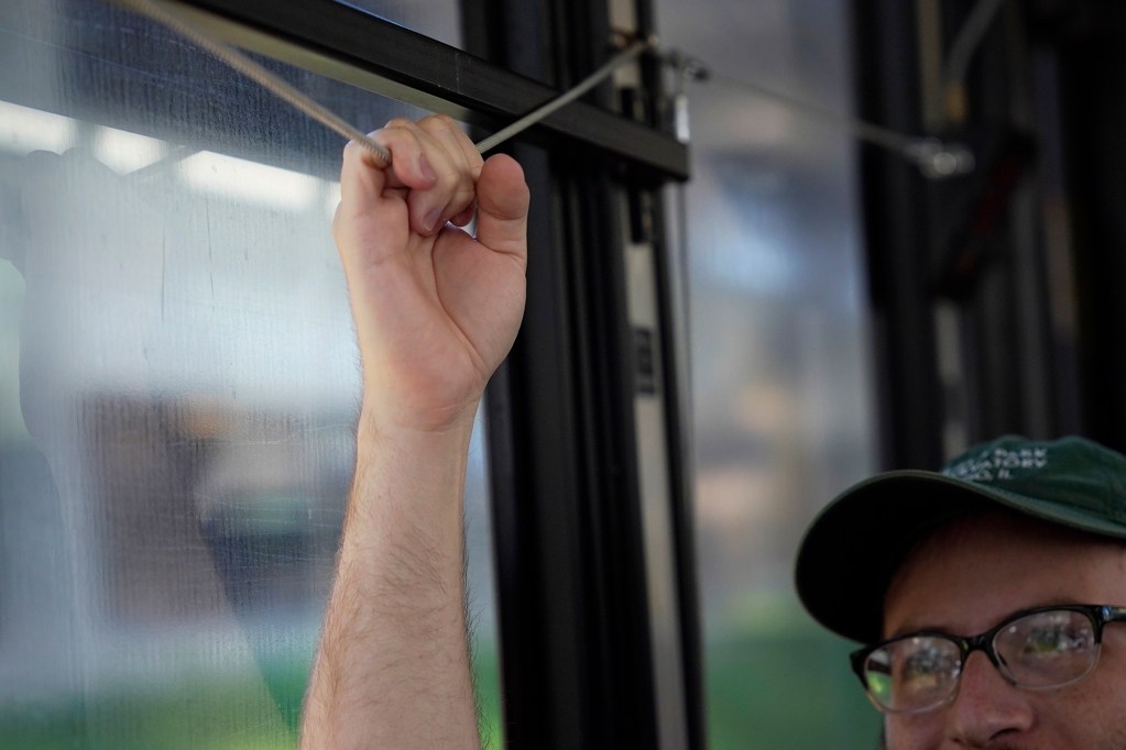 Reed Mershon pulls the cable for his stop on The Bus route 18 Thursday, Aug. 15, 2024, in Honolulu. Merson has been riding this bus for two years. The route will be discontinued. Some regular riders have found a community with each other and the driver. (Kevin Fujii/Civil Beat/2024)