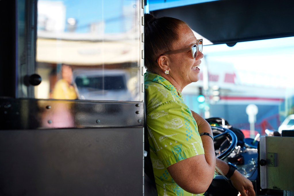 The Bus route 18 driver Kathy Paiva drops off a passenger on the route’s final lap Thursday, Aug. 15, 2024, in Honolulu. Paiva has been driving for 28 years. The route will be discontinued. Some regular riders have found a community with each other and the driver. (Kevin Fujii/Civil Beat/2024)