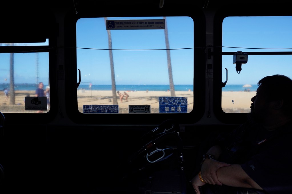 Brendan Mar of Honolulu rides The Bus route 18 along Queens Beach as it makes its last rounds Thursday, Aug. 15, 2024, in Honolulu. The route will be discontinued. Some regular riders have found a community with each other and the driver. This circuit includes changing from route 18 to 24. (Kevin Fujii/Civil Beat/2024)