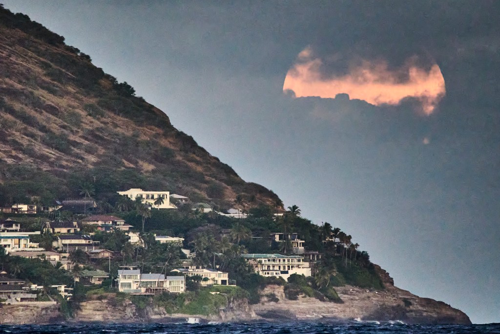 The partial eclipse of the Full Harvest Super Moon as viewed from Huakai Beach looking toward the China Walls area of Oahu’s south shore at 6.39.33 pm (Black & white image) and 33 seconds later as a Color image. Unfortunately the near atmosphere did not cooperate and we were only treated to a partial-partial eclipse. But we have another opportunity to see an atmospheric phenomena on October 2nd when the Sun will be eclipsed as it rises. (David Croxford/Civil Beat/2024