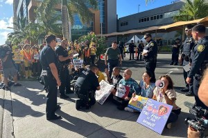 In this photo provided by Ashley Young, Honolulu police officers talk to demonstrators sitting outside a medical center in Honolulu, Monday, Sept. 23, 2024, where unionized nurses have been locked out since going on a one-day strike. (Ashley Young via AP)