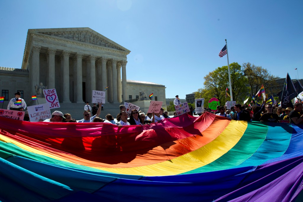 Demonstrators stand in front of a rainbow flag of the Supreme Court in Washington, Tuesday, April 28, 2015. The Supreme Court is set to hear historic arguments in cases that could make same-sex marriage the law of the land. The justices are meeting Tuesday to offer the first public indication of where they stand in the dispute over whether states can continue defining marriage as the union of a man and a woman, or whether the Constitution gives gay and lesbian couples the right to marry. (AP Photo/Jose Luis Magana)