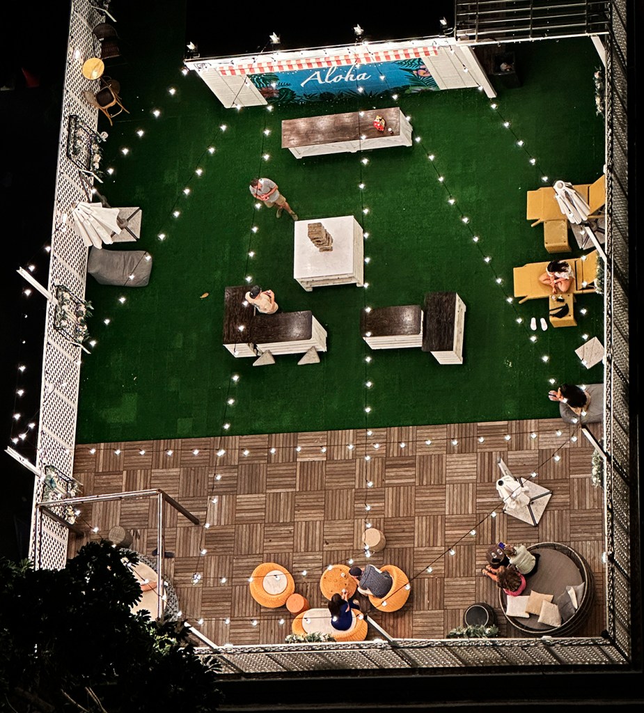 Guests play a giant Jenga and lounge on the roof of The Beach Waikiki Hostel Saturday, Sept. 28, 2024, in Honolulu. The bird’s-eye view was captured from the Queen Kapiolani Hotel penthouse. (Kevin Fujii/Civil Beat/2024)