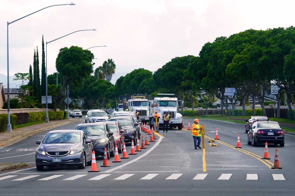 Workers re-stripe Iroquois Road on the Diamond Head side of Fort Weaver Road Tuesday, Oct. 8, 2024, in Ewa Beach. (Kevin Fujii/Civil Beat/2024)