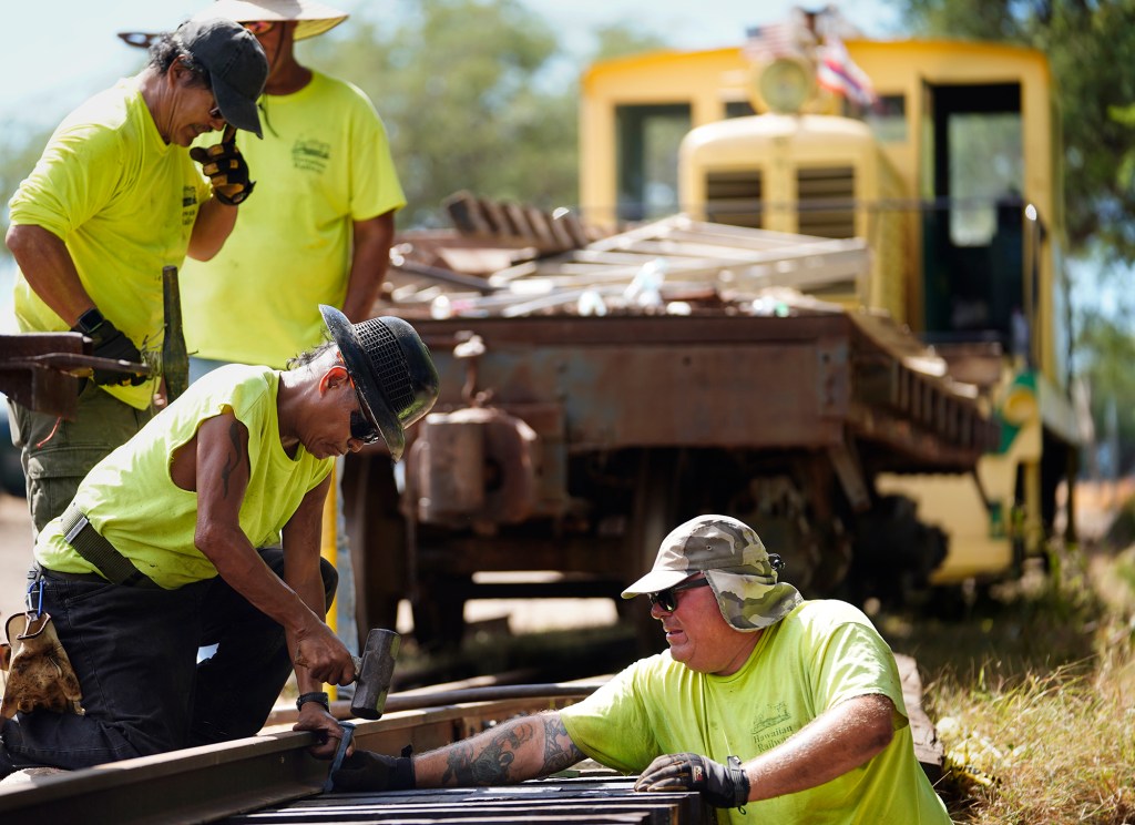 Hawaiian Railway Society crew members repair a section of their tracks at Kahe Point Beach Park Friday, Oct. 18, 2024, in Kapolei. They transported themselves aboard their diesel-engine locomotive while a flatbed car carried materials needed which included railroad ties, spikes and rails. (Kevin Fujii/Civil Beat/2024)