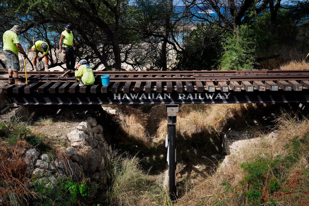 Hawaiian Railway Society crew members repair a section of their tracks at Kahe Point Beach Park Friday, Oct. 18, 2024, in Kapolei. They transported themselves aboard a diesel-engine locomotive and materials on a flatbed car. Vandals damaged this section of their tracks which is approximately the half-way point of their educational tours where a narrator talks story about the history of the train (Kevin Fujii/Civil Beat/2024)
