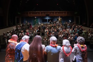 Storytellers gather on stage as the audience applauds the featured Kupuna