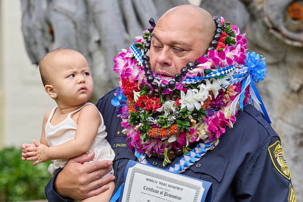 Forty-five officers and civilians were recognized during a promotion ceremony at the Mission Memorial Auditorium on November 19th. Brooklyn Spacek, the one year old granddaughter of HPD CID Sergeant Tracy Spacek  exchanged a glance with her grandad following the ceremony during a photo opp.(David Croxford/Civil Beat/2024)