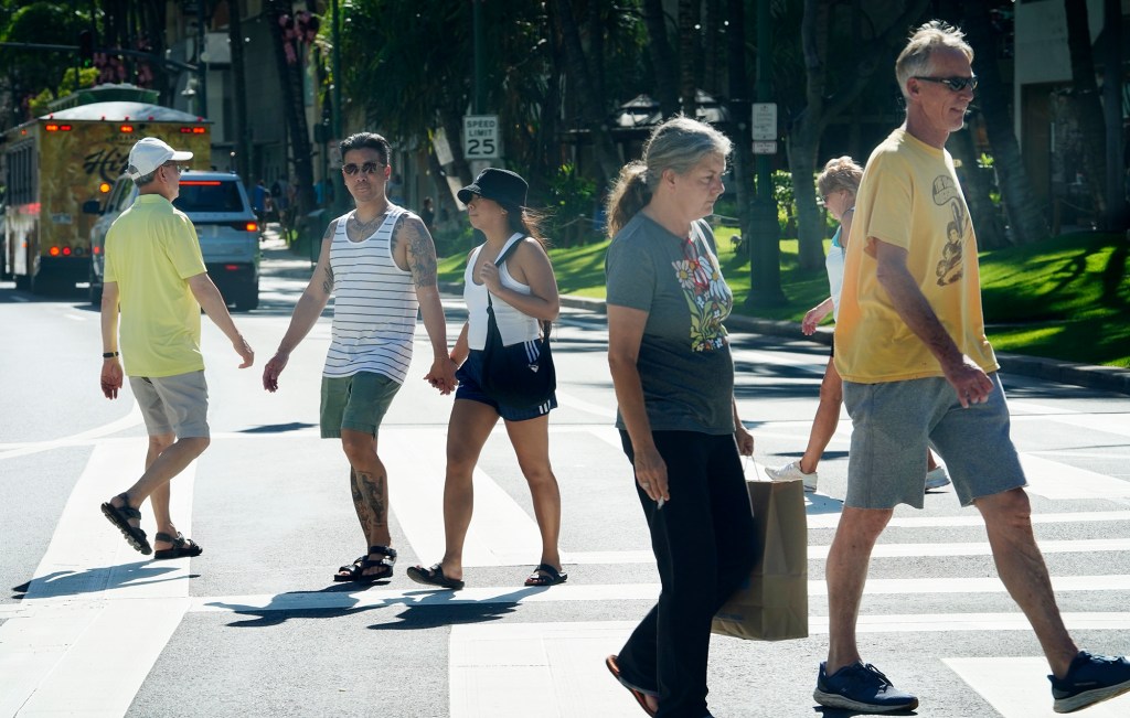Waikiki visitors cross Kalākaua Avenue at Royal Hawaiian Avenue Thursday, Dec. 4, 2024, in Honolulu. All vehicular traffic stops and pedestrians also may cross diagonally. (Kevin Fujii/Civil Beat/2024)
