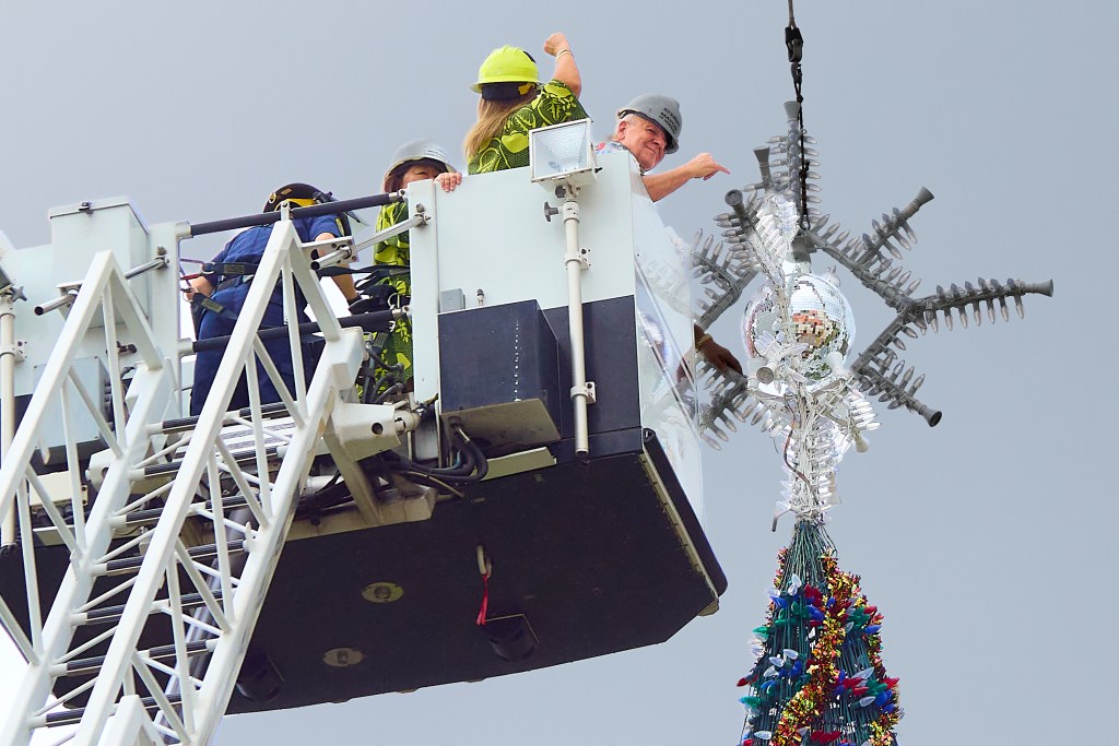 Honolulu’s Santa and Mrs Claus decorations arrived at Honolulu Hale on the trailer of a long flatbed truck that itself was quite a site as it came to a halt on Punchbowl Street.  They sat  ready to be offloaded by a crane to their positions outside Honolulu Hale. The Festive pair will be one of the main display elements for the Honolulu City Lights Parade on December 7th (David Croxford/Civil Beat/2024)
