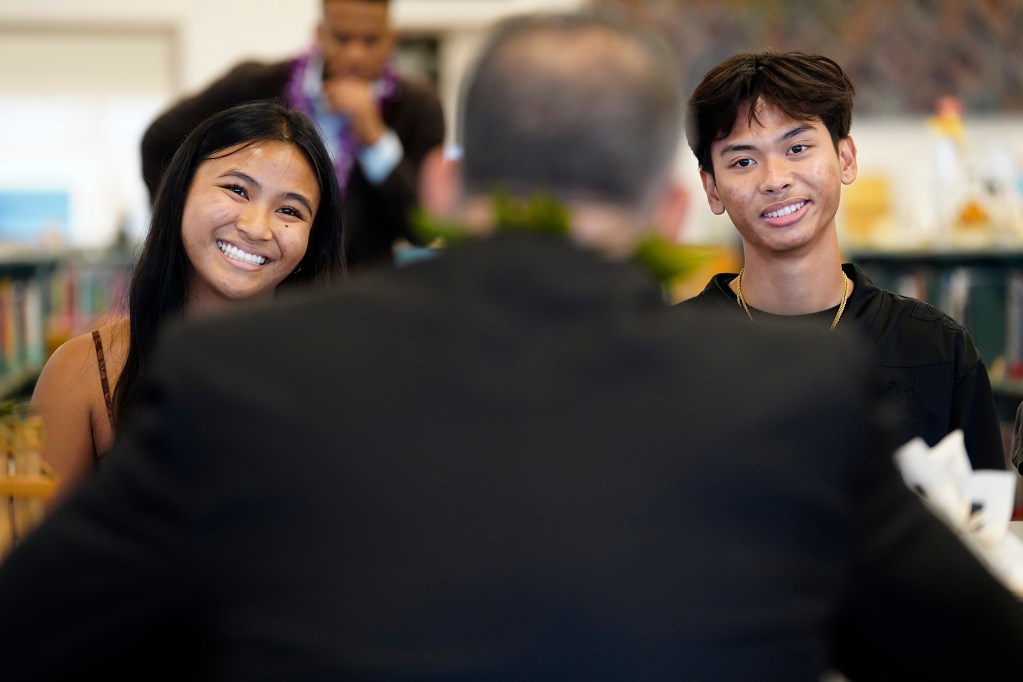 Lahainaluna High School student leaders Karisa Bayudan, left, and Mobi Adovas enjoy a light moment with U.S. Department of Education Sec. Miguel Cardona during his West Maui tour Friday, Dec. 6, 2024, in Lahaina. (Kevin Fujii/Civil Beat/2024)