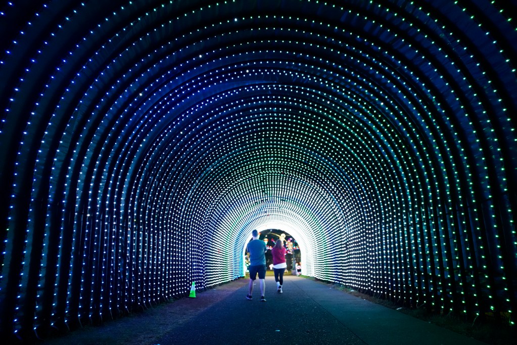 Rob and Johanna Rawson of Honolulu walk through the City and County of Honolulu and Friends of Honolulu City Lights tunnel early Sunday morning, Dec. 8, 2024, in Honolulu. The Rawsons came to cheer on a friend running in the Honolulu Marathon. (Kevin Fujii/Civil Beat/2024)