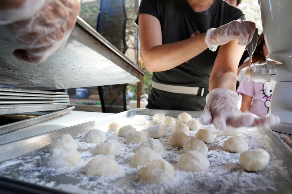 Mochi is cut and placed on cookie sheets with flour to prevent sticking during a mochitsuki demonstration Saturday, Dec. 14, 2024, at the Japanese Cultural Center of Hawai’i in Honolulu. Mochigome (glutinous rice) is pounded into a chewy cake for a new year’s treat. It’s a celebrated food to offer good luck, prosperity, unity, trust and good health for the new year. (Kevin Fujii/Civil Beat/2024)