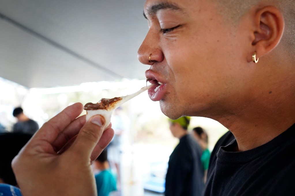 Konko Mission of Wahiawa volunteer Evan Davison of Honolulu, enjoys a mochi with Nutella he made after pounding mochi during a mochitsuki demonstration Saturday, Dec. 14, 2024, at the Japanese Cultural Center of Hawai’i in Honolulu. (Kevin Fujii/Civil Beat/2024)