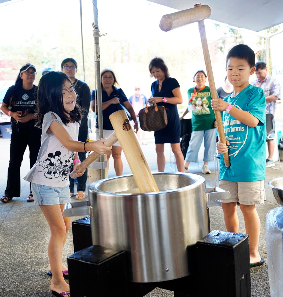 Lindsey Lum, 8, and her brother Logan Lum, 10, take turns pounding mochi during a Konko Mission of Wahiawa mochitsuki demonstration Saturday, Dec. 14, 2024, at the Japanese Cultural Center of Hawai’i in Honolulu. (Kevin Fujii/Civil Beat/2024)