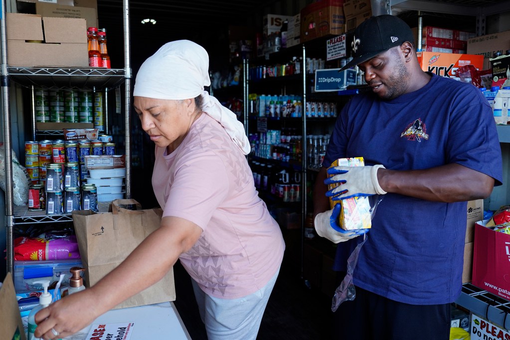Lahaina Resource & Recovery Center Aquino, Etina “Edna” Hingano, left, and LaVatus “Vegas” Donerson restock food supplies Thursday, Dec. 19, 2024, in Wailuku. Edna and Vegas both lost their homes and belongings in the Aug. 8, 2023, Lahaina fire. (Kevin Fujii/Civil Beat/2024)