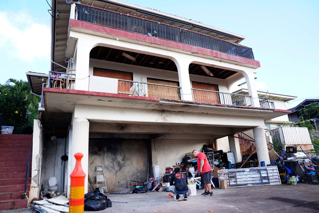 Lance Jordan, right, of Kaneohe, and an unidentified passenger from his truck leave flowers at a home where a deadly, New Year’s Eve fireworks explosion took place Thursday, Jan. 2, 2025, in Honolulu’s Salt Lake neighborhood. Multiple fatalities and injuries were reported. Jordan, 30, grew up on this street but has since moved to Kaneohe. (Kevin Fujii/Civil Beat/2025)